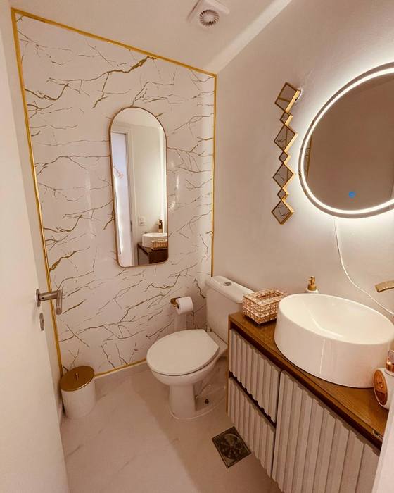 Lavabo do consultório, com bancada de madeira, cuba branca e espelho iluminado.