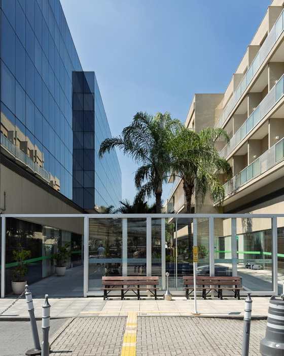 Entrada do edifício na Avenida Ayrton Senna, com bancos e cobertura de vidro.